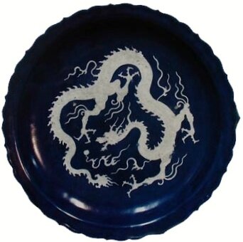 Foliate rim plate decorated in white slip with relief dragon and clouds on a cobalt-blue glaze, Yuan Dynasty (1279-1368). Diameter: 46cm. Height: 7.3cm. Ex the Ardabil Shrine, now National Museum of Iran.